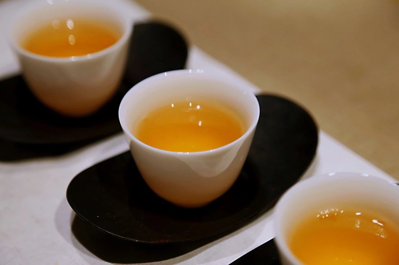 Golden tea liquor poured into a tasting cup